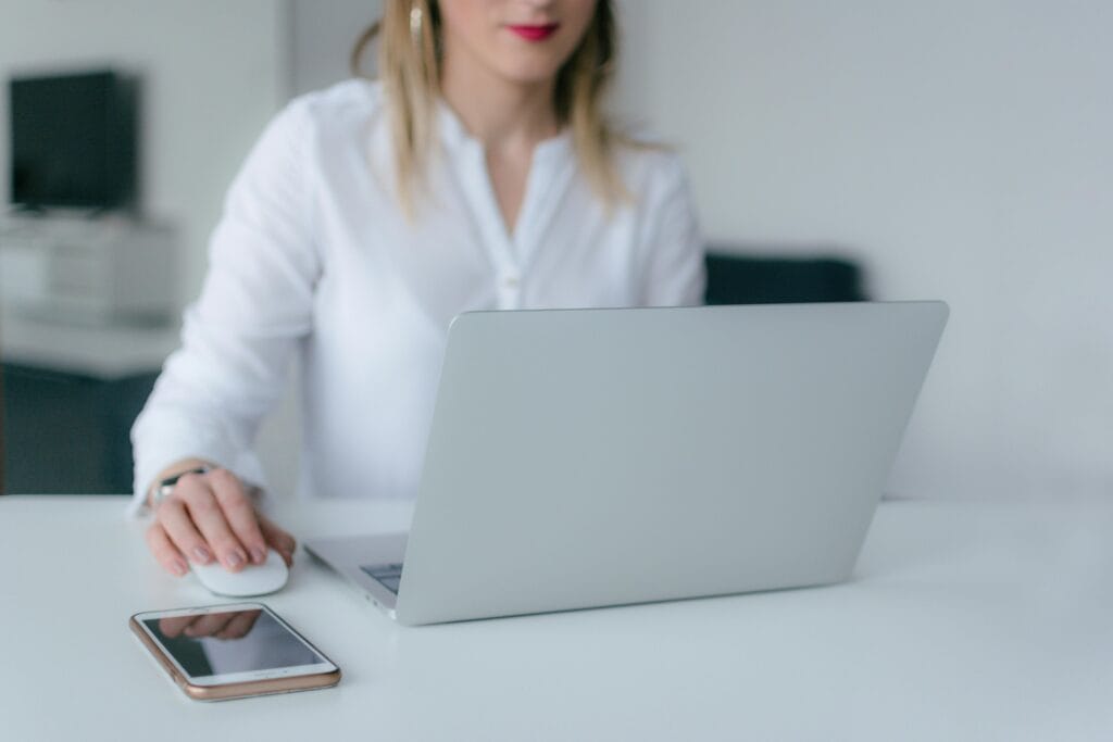 Mobile & Online Notary | Austin, Travis County A woman working at a desk using a laptop and smartphone, exemplifying remote work.
